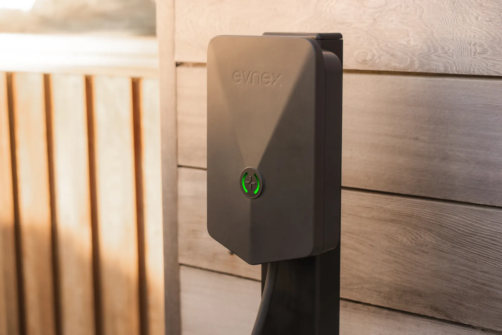 Evnex E2 smart EV charger mounted on warm timber wall with green LED indicator