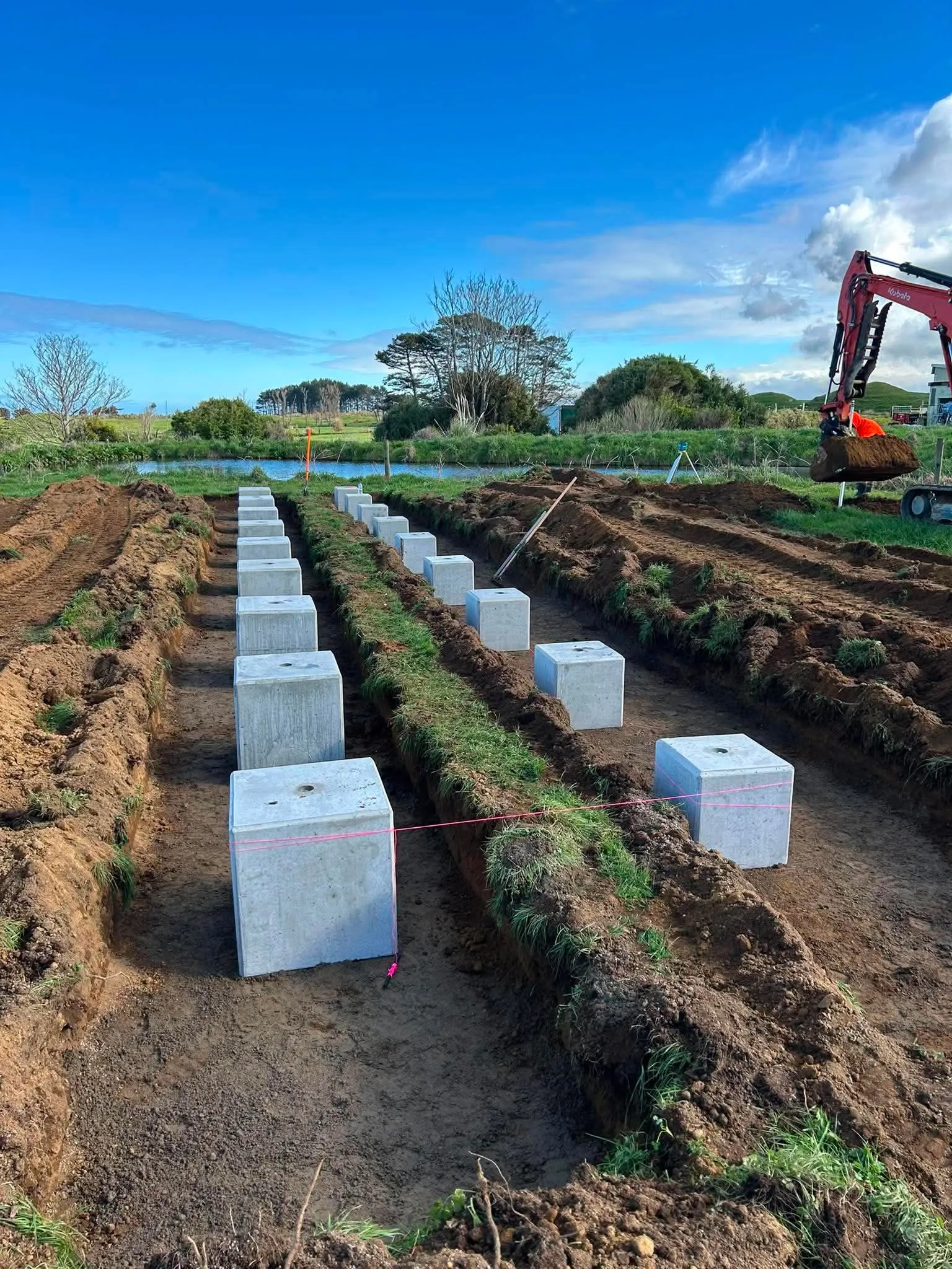 Concrete foundation blocks being installed for ground-mounted solar on a Taranaki farm