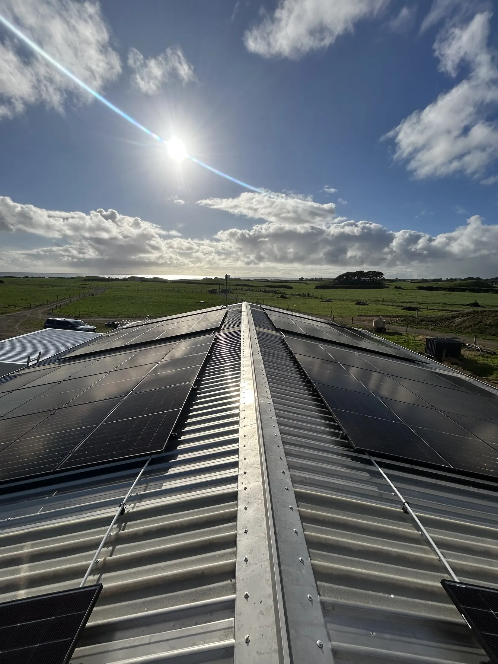 Large dual-roof solar array on a coastal Taranaki dairy shed