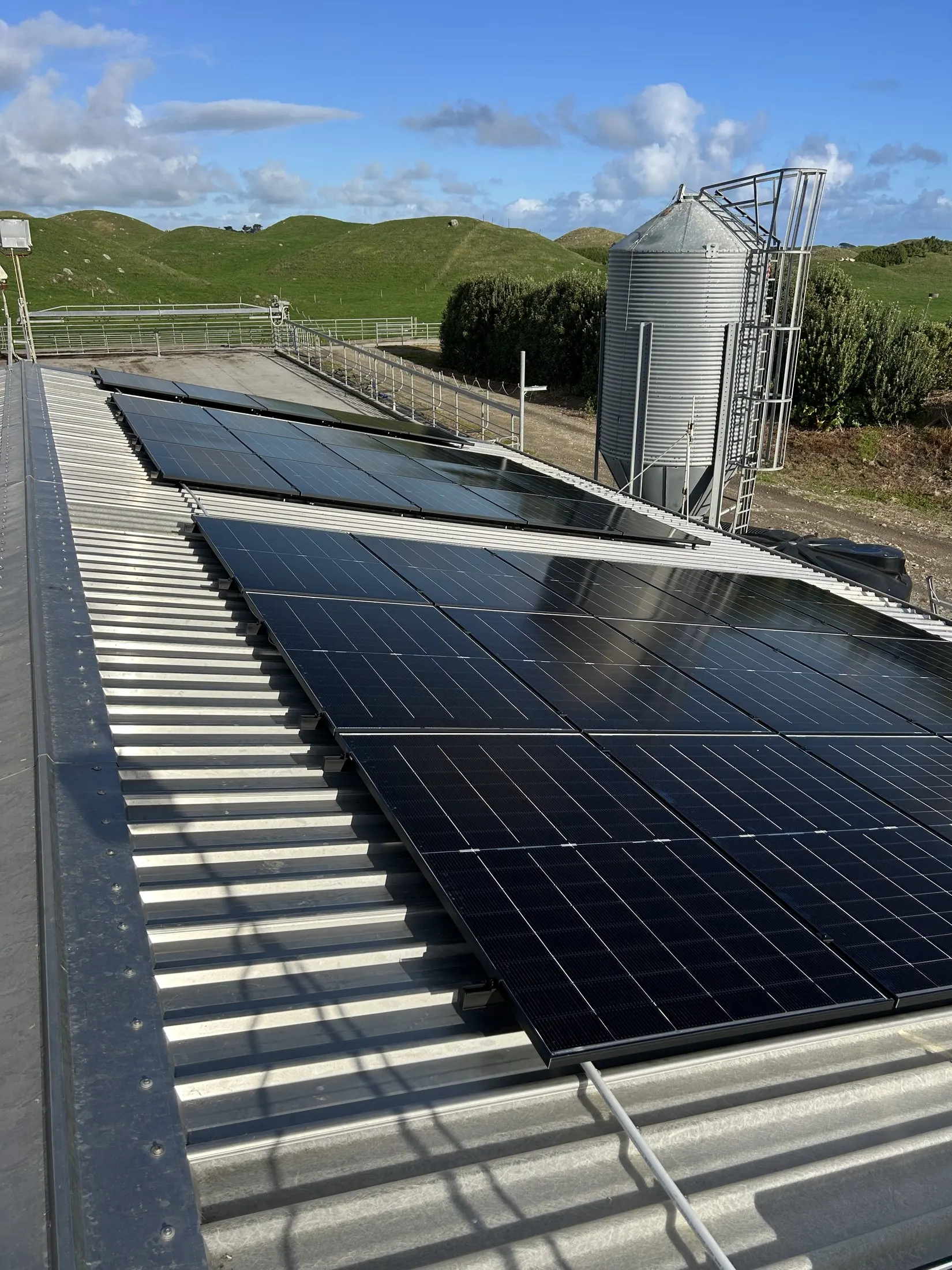 Dairy shed roof solar panels beside farm silos in Taranaki