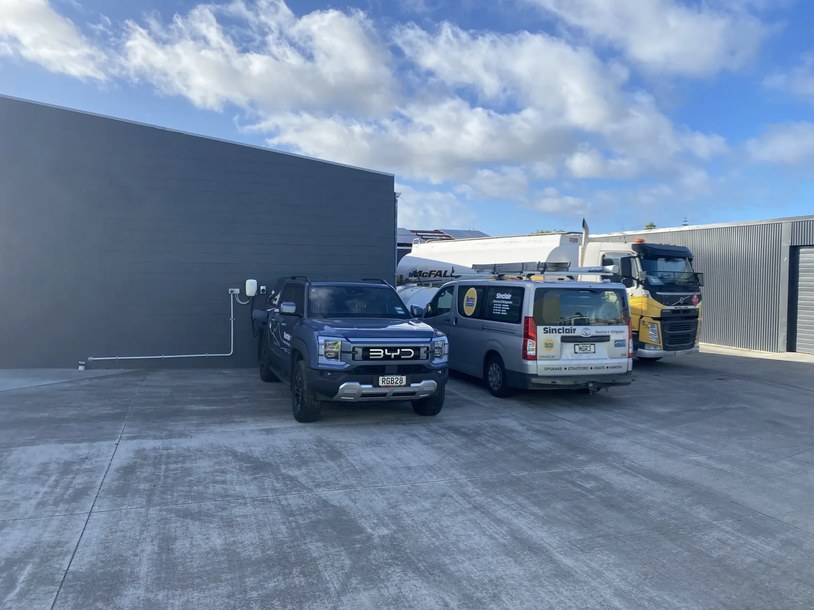 BYD Shark ute at Sungrow EV charger with solar arrays visible on the workshop roof